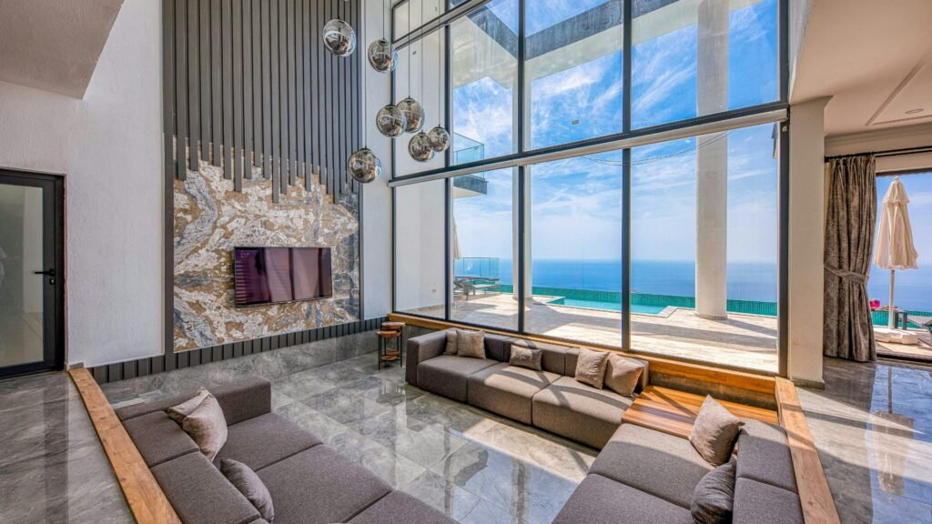 Living room with ocean view windows, marble wall, lights, and furniture.