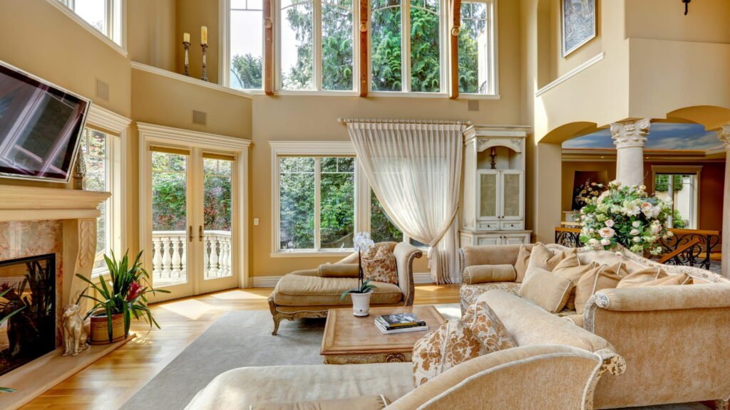 Living room with sofa, coffee table, plants, and large windows.
