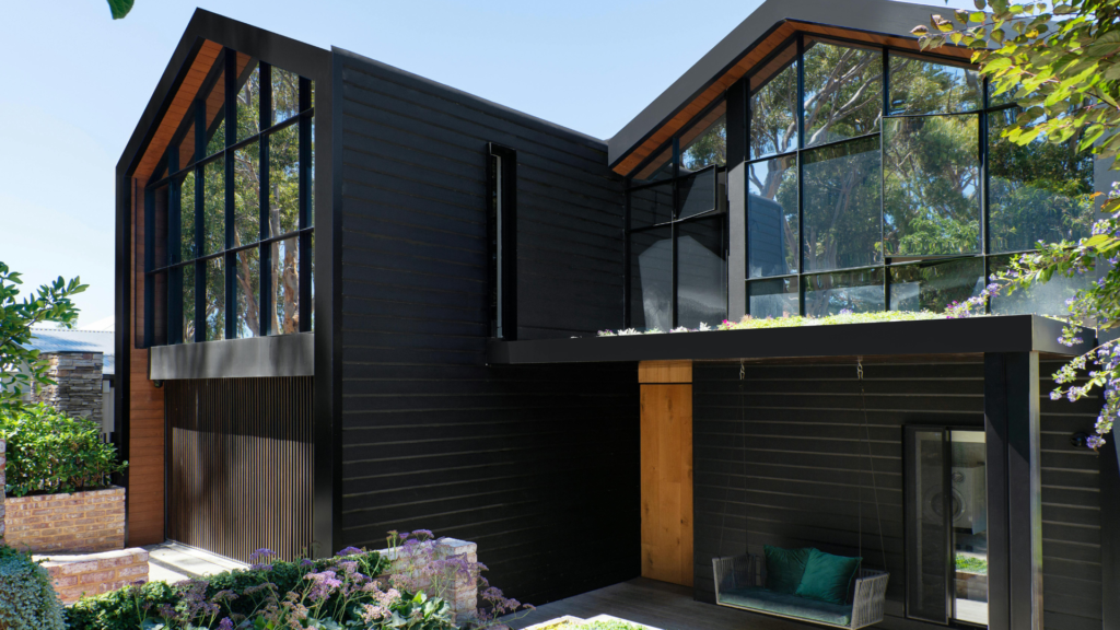 California real estate house with black exterior, large windows, and greenery.